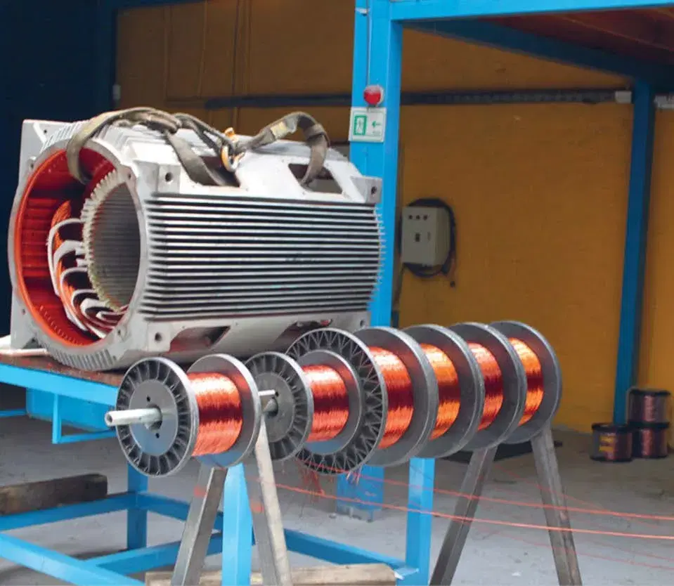 Motor eléctrico industrial en proceso de bobinado junto a carretes de alambre de cobre